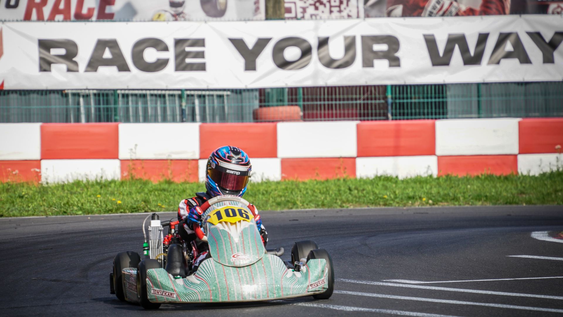 Maximilian Willamowski im Tony Kart mit der Nummer 106 vor dem Banner „Race your way“ in Kerpen